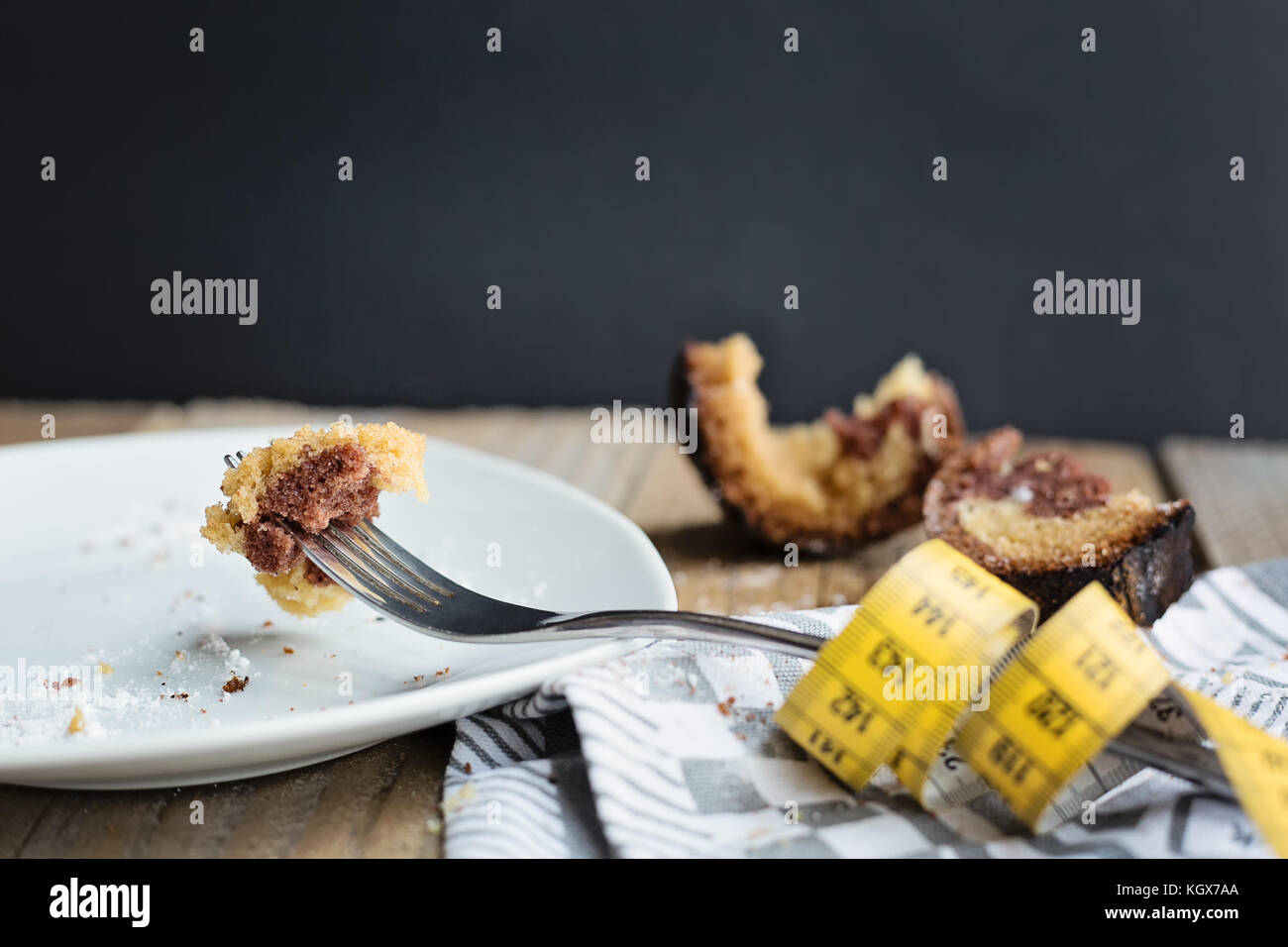 Morceau de gâteau empalé sur une fourche à l'aide d'un ruban sur le coté et casse de la moitié-mangé du gâteau à l'arrière-plan Banque D'Images