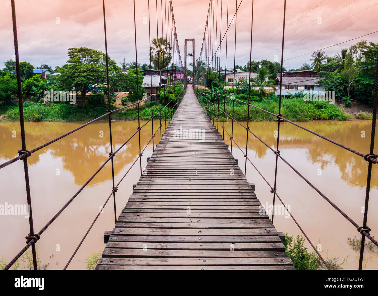 Pont suspendu de corde à travers une rivière en crue, au crépuscule, en Thaïlande Banque D'Images