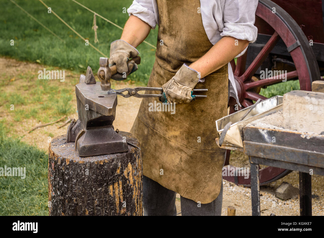 Blacksmith travaille sur un objet en fer avec un marteau pendant un atelier. Banque D'Images
