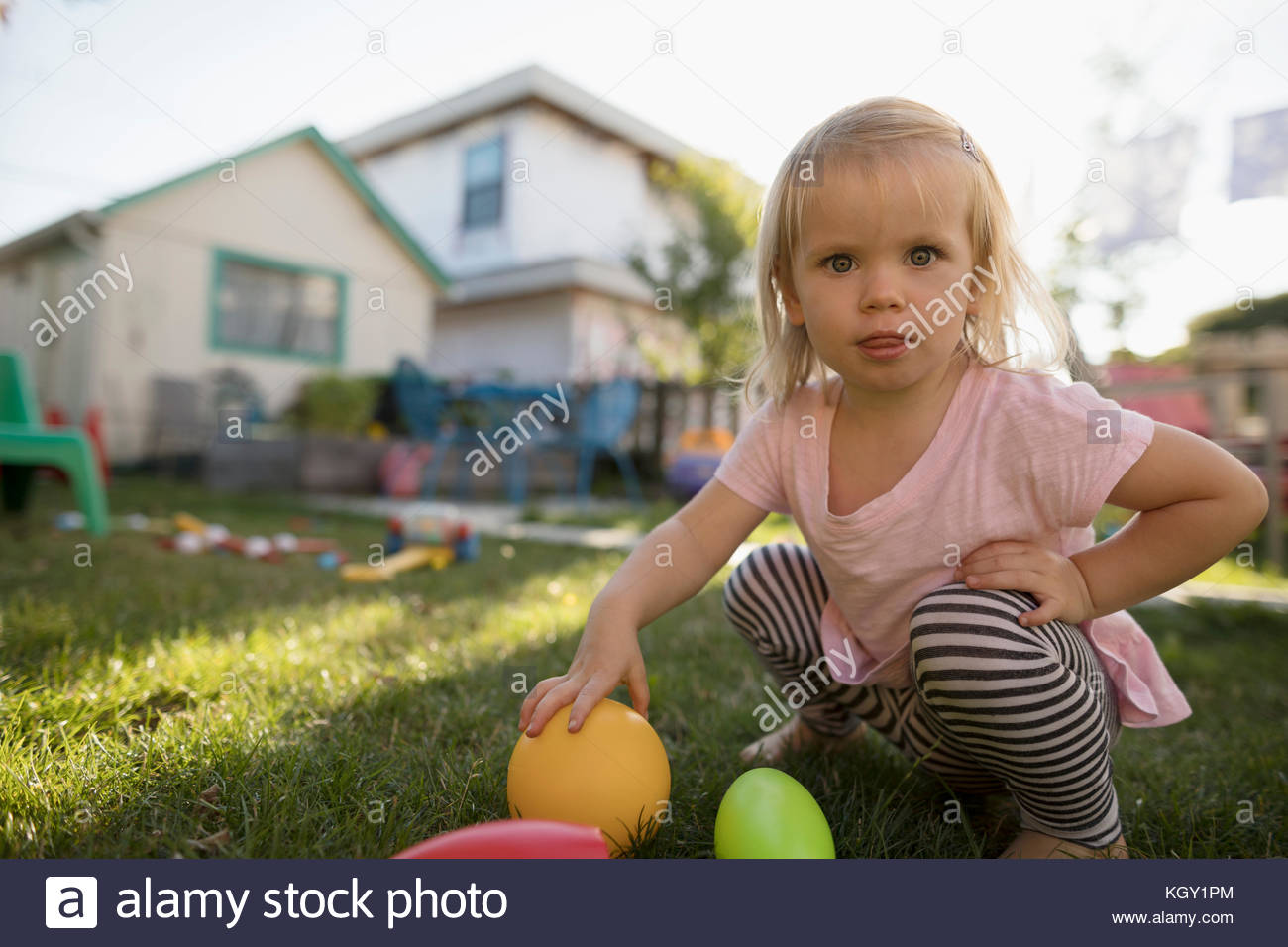 Curieux Portrait blonde girl Playing with toys in backyard Banque D'Images
