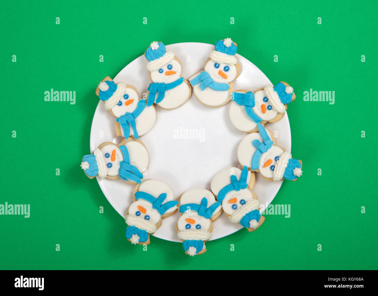 Le SNOWMAN sugar cookies décorés de marshmallow fondant, le glaçage royal  bleu foulard et chapeau disposées en cercle sur une assiette de porcelaine.  fond vert Photo Stock - Alamy