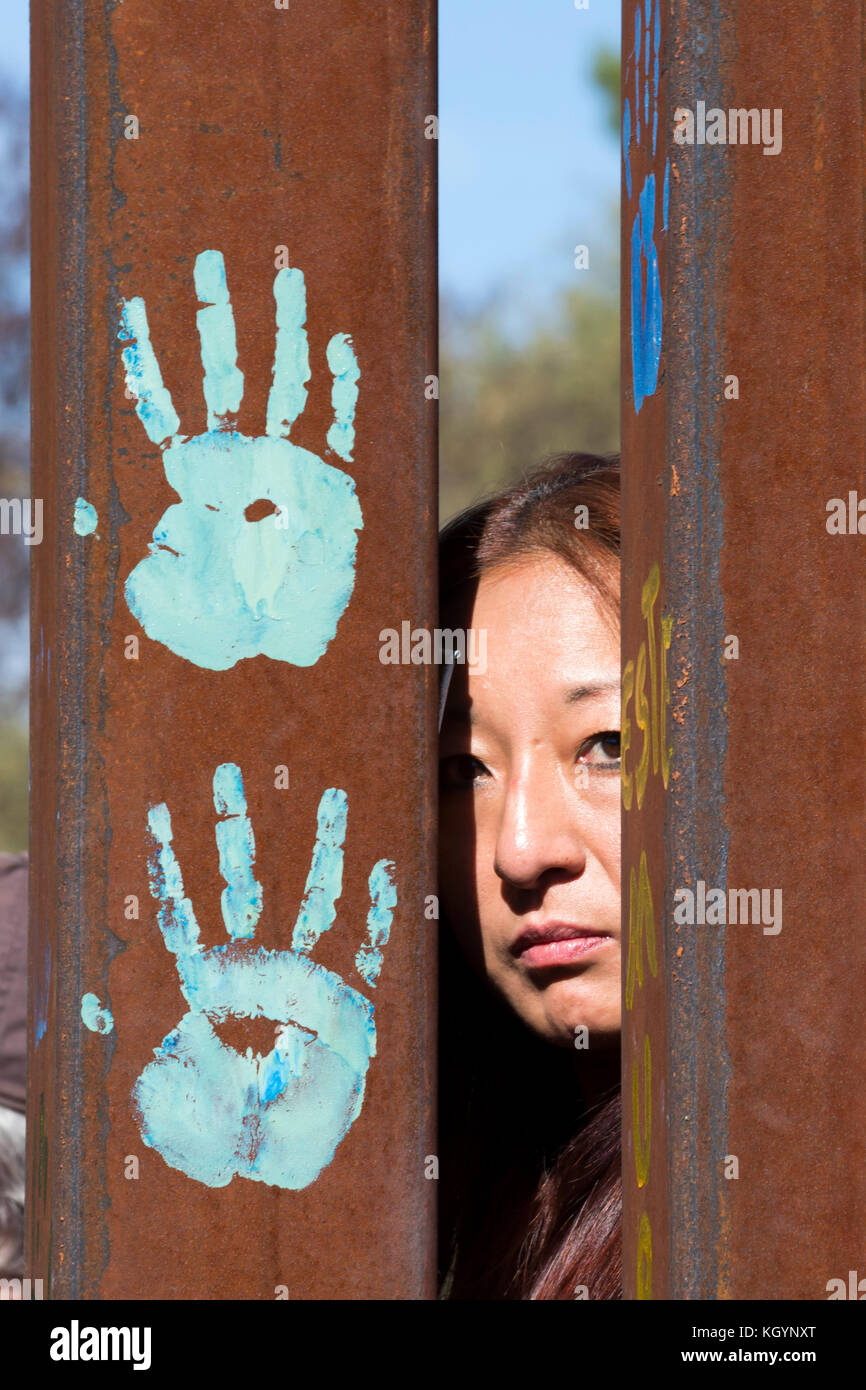 Nogales, Arizona usa et Nogales, Sonora Mexique - 11 novembre 2017 - Une femme regarde à travers la frontière comme des rassemblements ont eu lieu des deux côtés de la clôture de l'appel d'immigration plus ouverte. l'événement a été organisé par l'école de l'Americas Watch, un groupe de religieux et des activistes communautaires. Banque D'Images