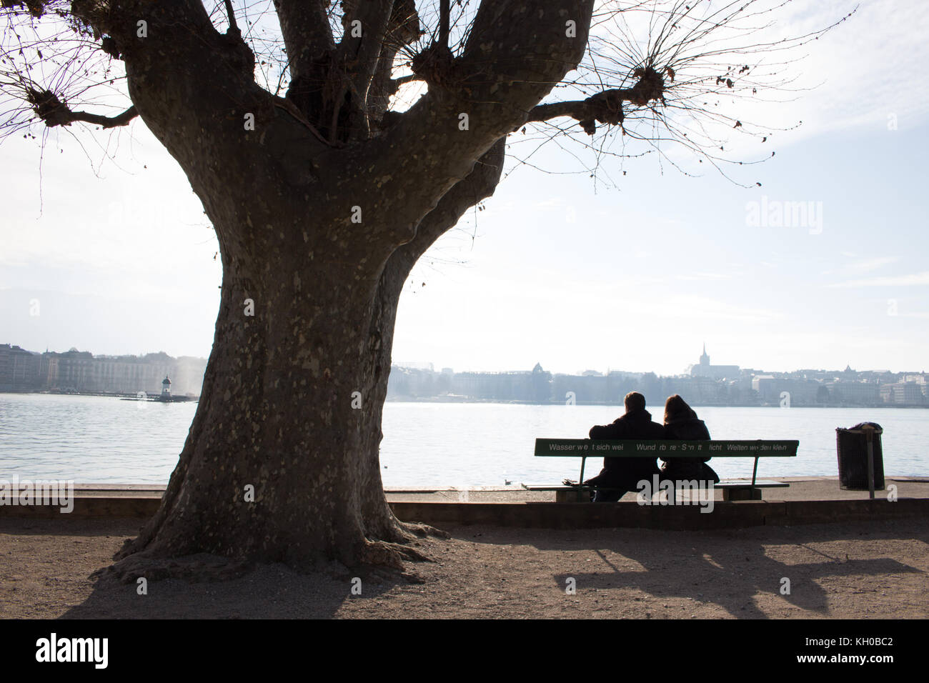 Deux personnes couple sitting on bench avec une belle vue sur la ville et de l'eau Banque D'Images