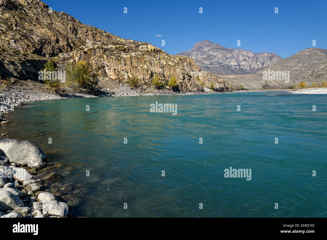 Automne lumineux vue sur les montagnes, la rivière avec de l'eau turquoise et de la plage avec des cailloux et des pierres sur un fond de ciel bleu dans un ciel ensoleillé Banque D'Images