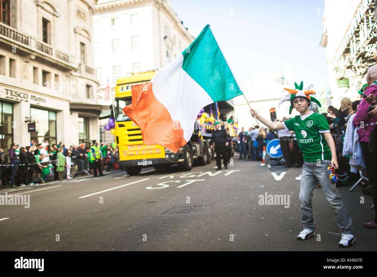 Un jeune participant agite le drapeau irlandais et porte un maillot national irlandais et un chapeau lors de la célébration de la fête de Patrick à Londres. ROYAUME-UNI 16/03 2014. Banque D'Images