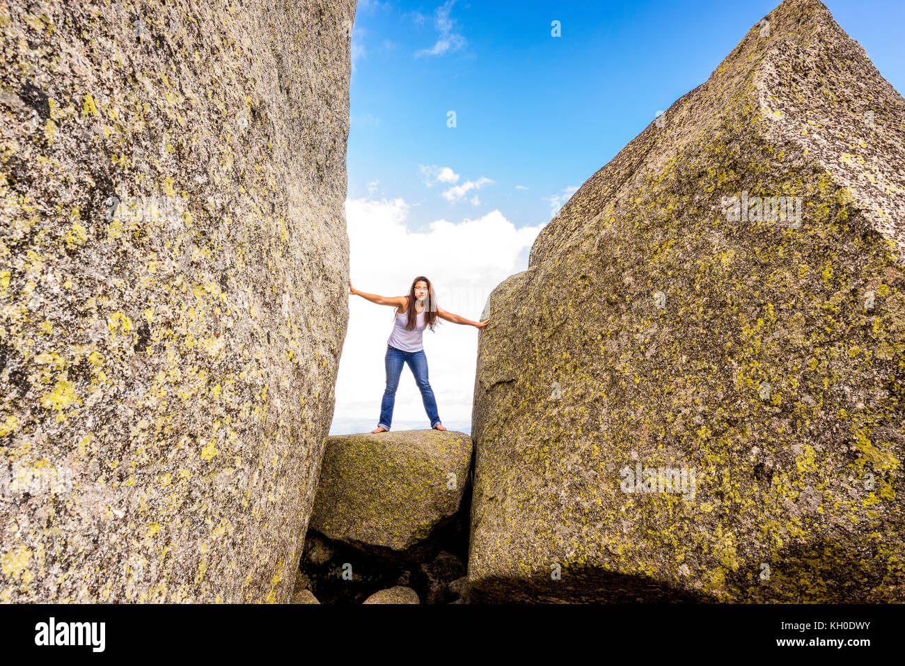Une femme étire ses bras et ses jambes entre les énormes blocs de granit au jardin des dieux du Mont Buffalo, Victoria Banque D'Images