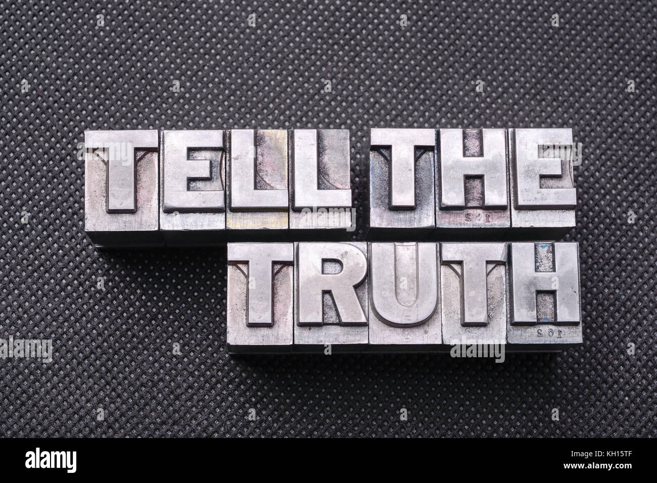 Dire la vérité mots fabriqués à partir de blocs de typogravure métallique sur la surface perforée noire Banque D'Images
