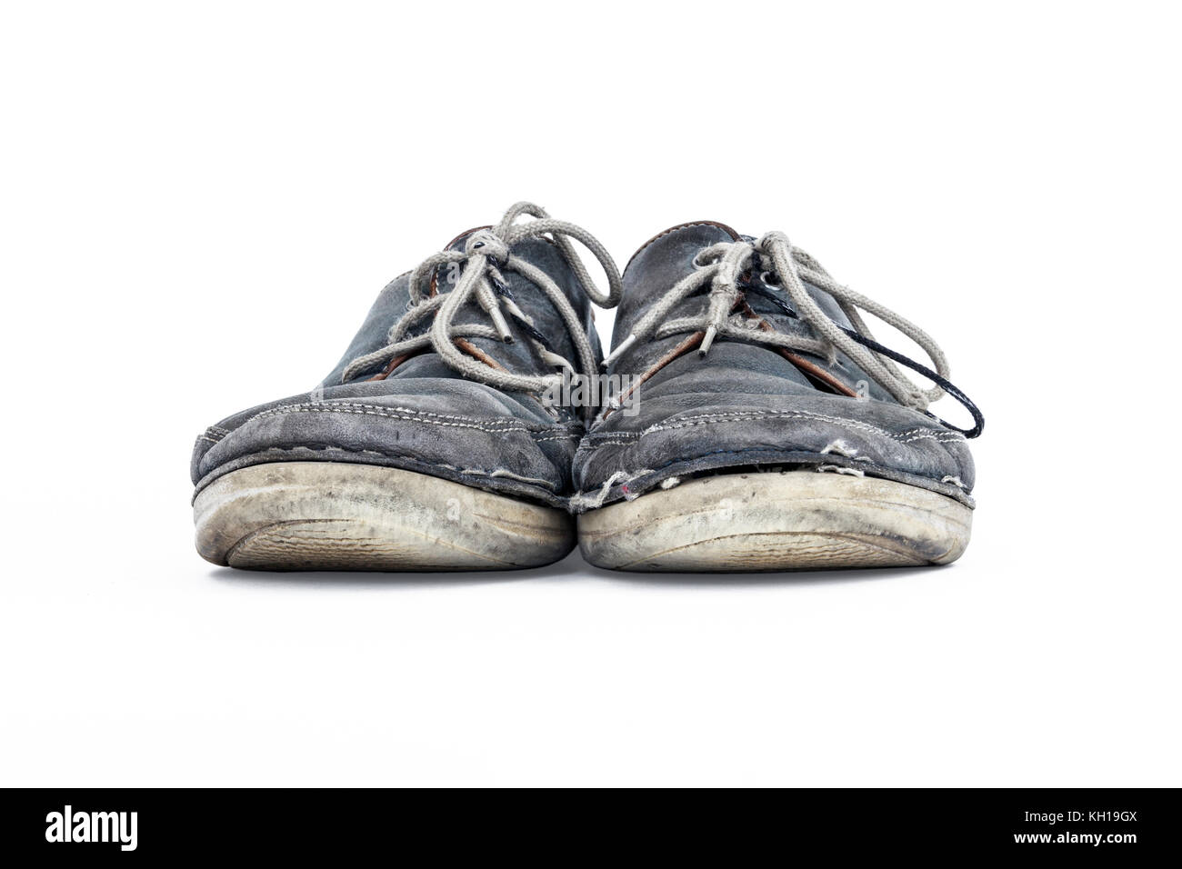 Une paire de vieux gris usé chaussures à lacets en cuir sur un fond blanc. Banque D'Images