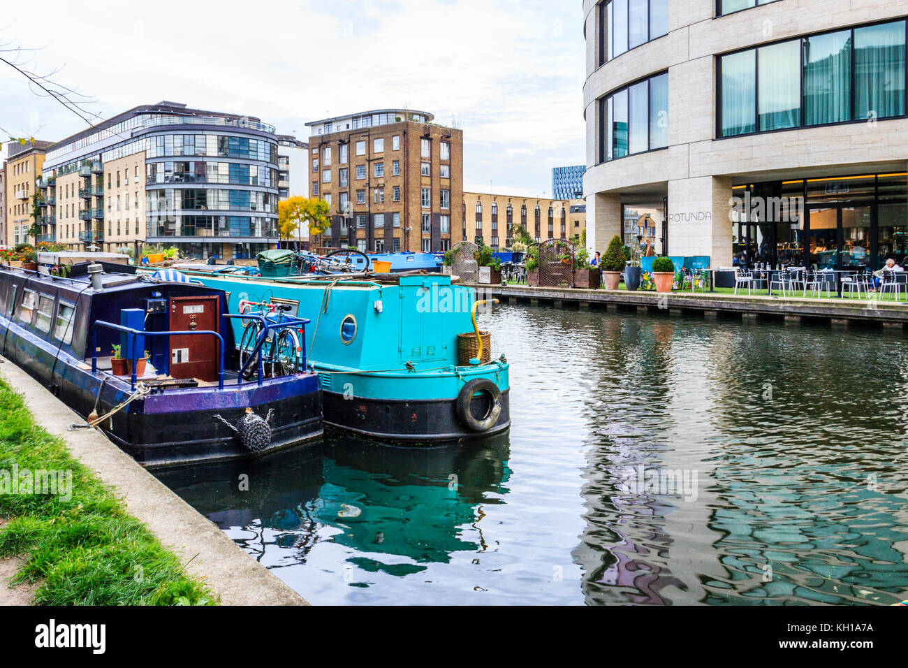 Amarré au bassin Battlebridge Narrowboats, King's Cross, Londres, Royaume-Uni, la Rotonde cafe dans la King's Place bâtiment en arrière-plan Banque D'Images