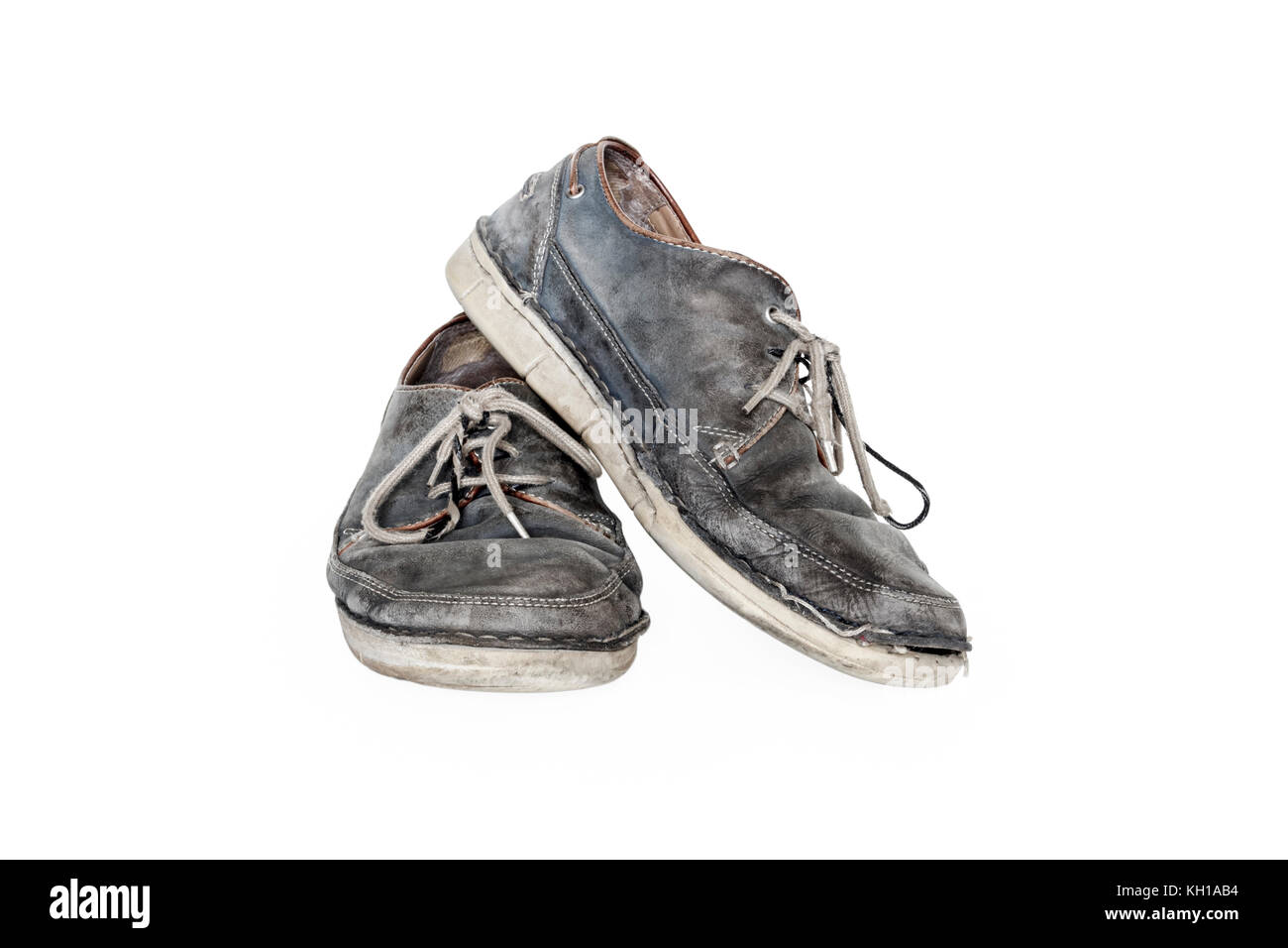 Une paire de vieux gris usé chaussures à lacets en cuir sur un fond blanc. Banque D'Images