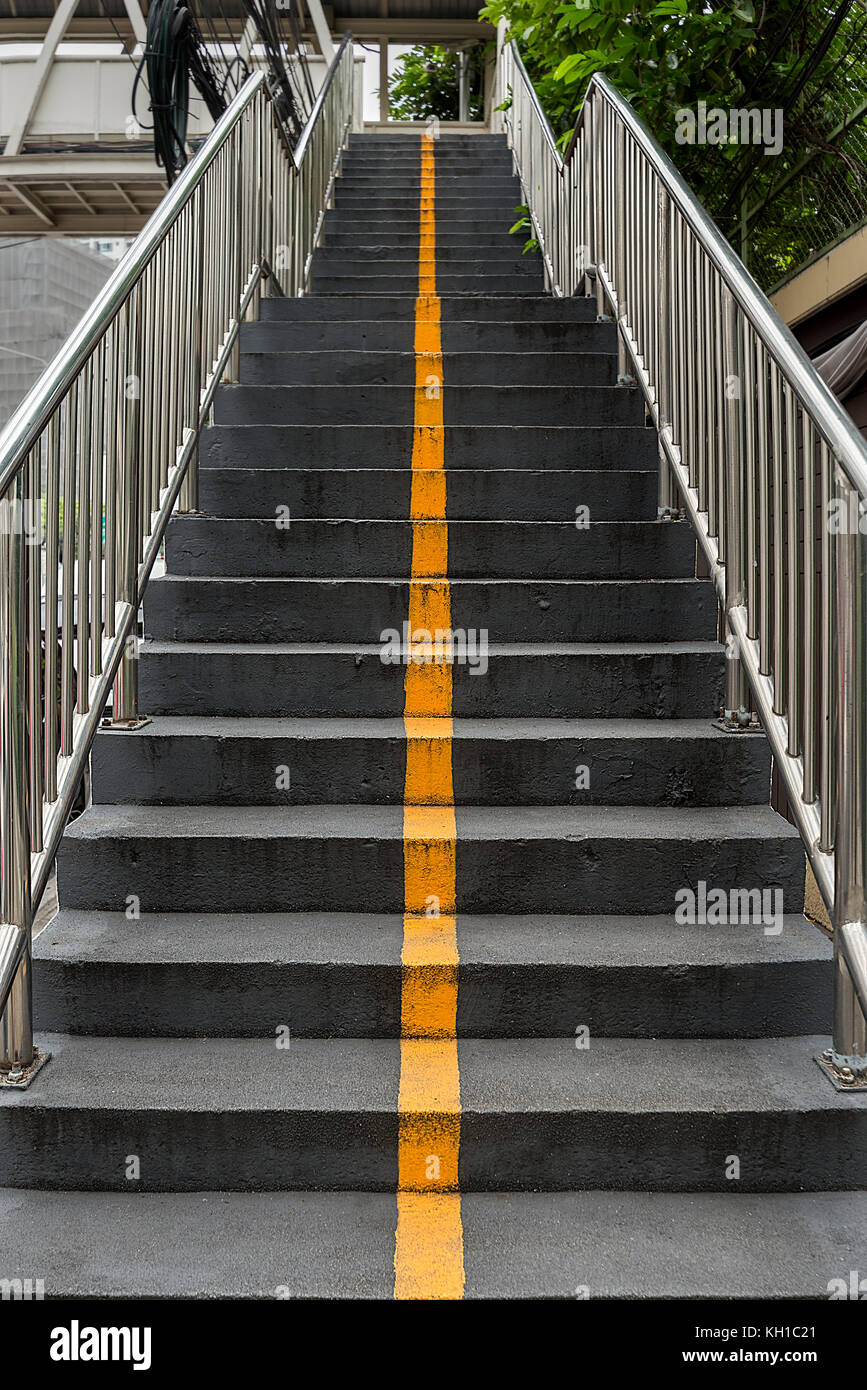 Une ligne jaune vif peint un escalier en béton qui les sépare de la ville de haut en bas et d'autre. Banque D'Images