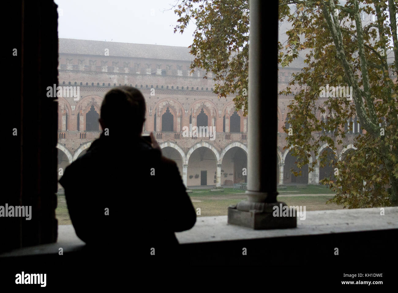 La silhouette d'une jeune fille de prendre une photo de Castello Visconteo à travers un parapet gothique lucent Banque D'Images