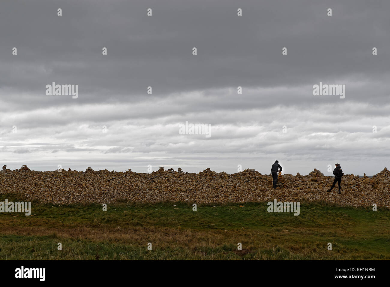 Un homme constructes un cairn sur la plage de l'île de Saint Banque D'Images