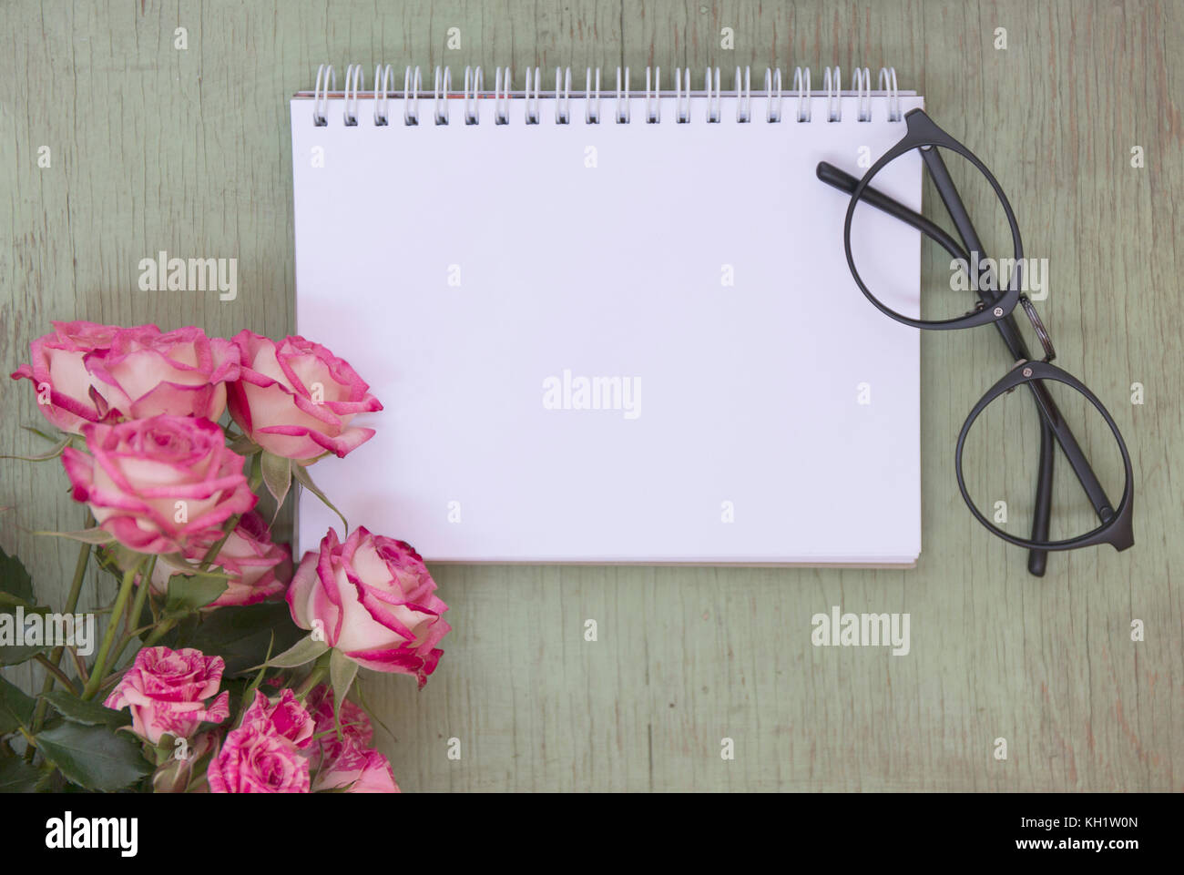 Ordinateur portable blanc des maquettes de l'art avec des roses roses. place pour le texte. Des fleurs fraîches et des lunettes noires. Banque D'Images