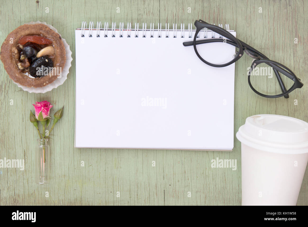 Ordinateur portable blanc des maquettes pour l'oeuvre avec rose rose et noir lunettes. place pour le texte. des fleurs. café d'aller et de gâteau. Banque D'Images