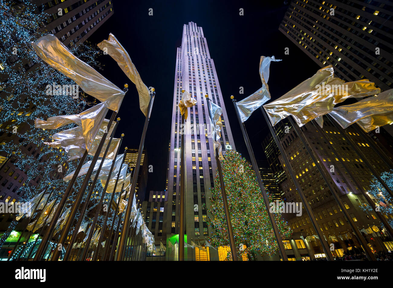 New york city - 21 décembre 2016 : maison de vacances drapeaux volent autour de la place centrale en face de l'arbre de Noël du Rockefeller Center, l'un des meilleurs de la ville. Banque D'Images