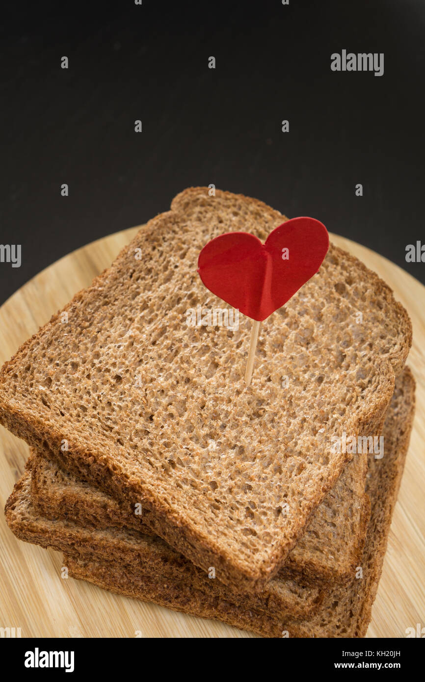 Tranche de pain sandwich de grains entiers avec broche coeur, avec un arrière-plan sombre. Banque D'Images