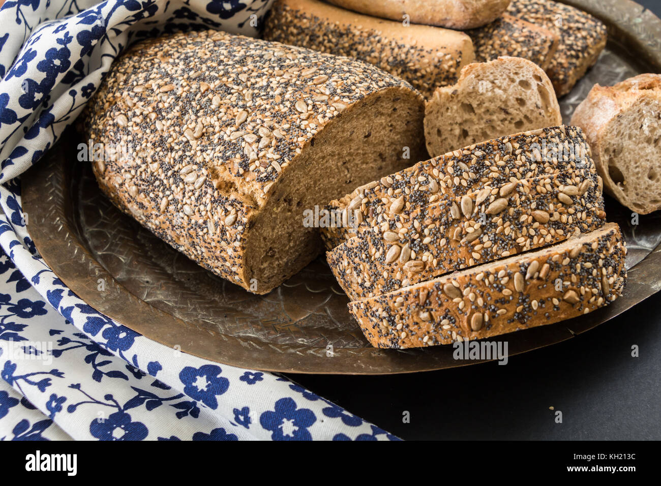 Pain de blé entier et pains sandwich, sur un plat oriental floral avec une serviette de cuisine Banque D'Images