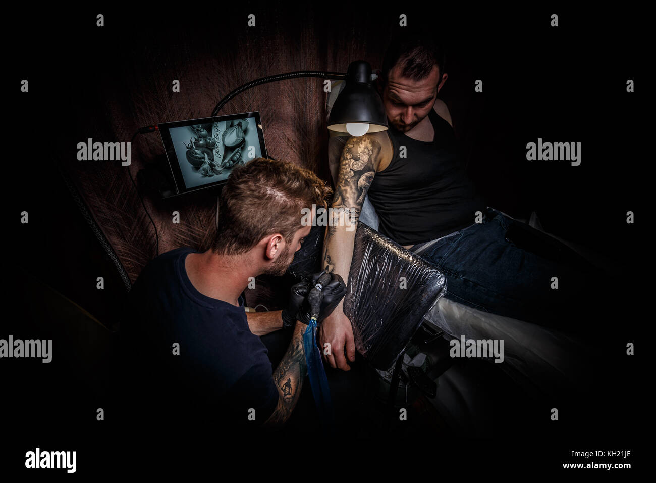 Portrait d'un homme maître de tatouage montrant un processus de création de tatouage dans une main d'homme sous la lampe Banque D'Images