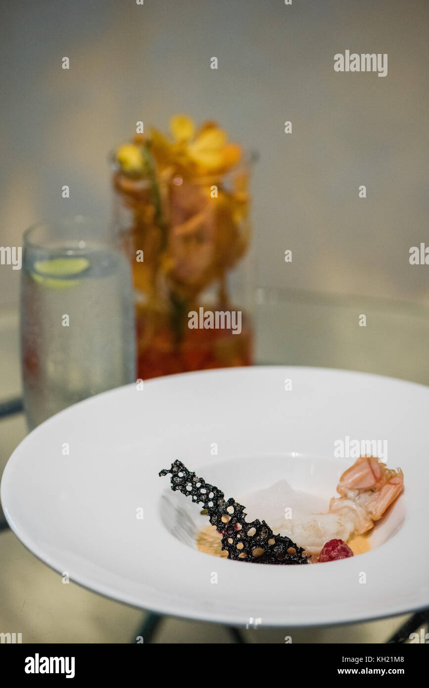 Une assiette de fruits de mer sur une table en verre avec un verre d'eau pétillante Banque D'Images