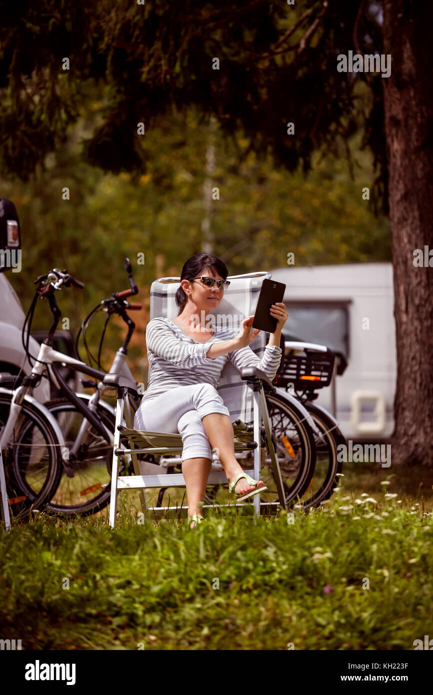 Femme regardant la tablette à côté du camping location de caravane .. vacances vacances familiales vacances, voyages voyage en camping rv. wi-fi informatio Banque D'Images