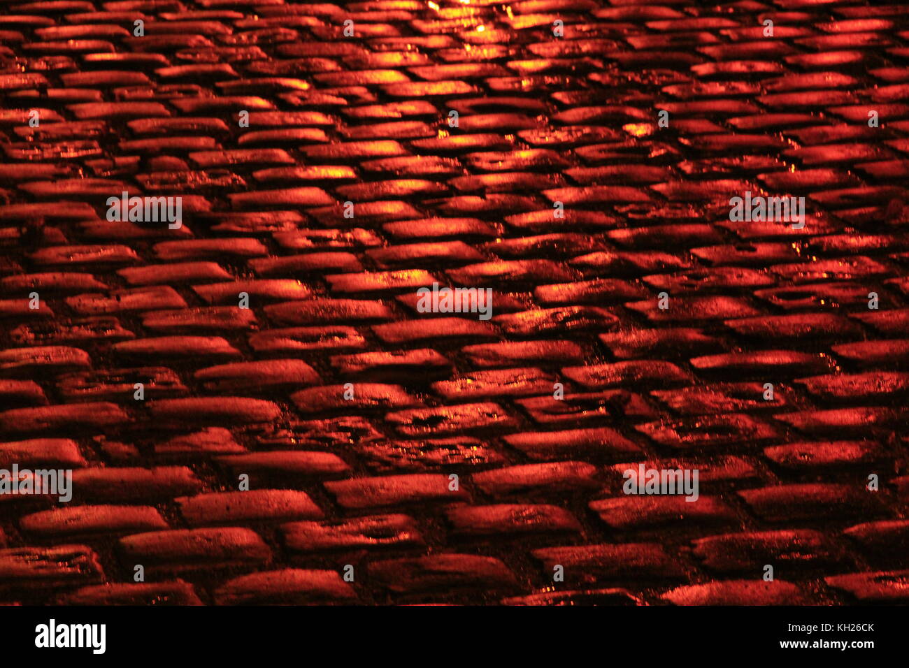 Route avec des pavés dans les feux rouges de la ville de nuit Banque D'Images