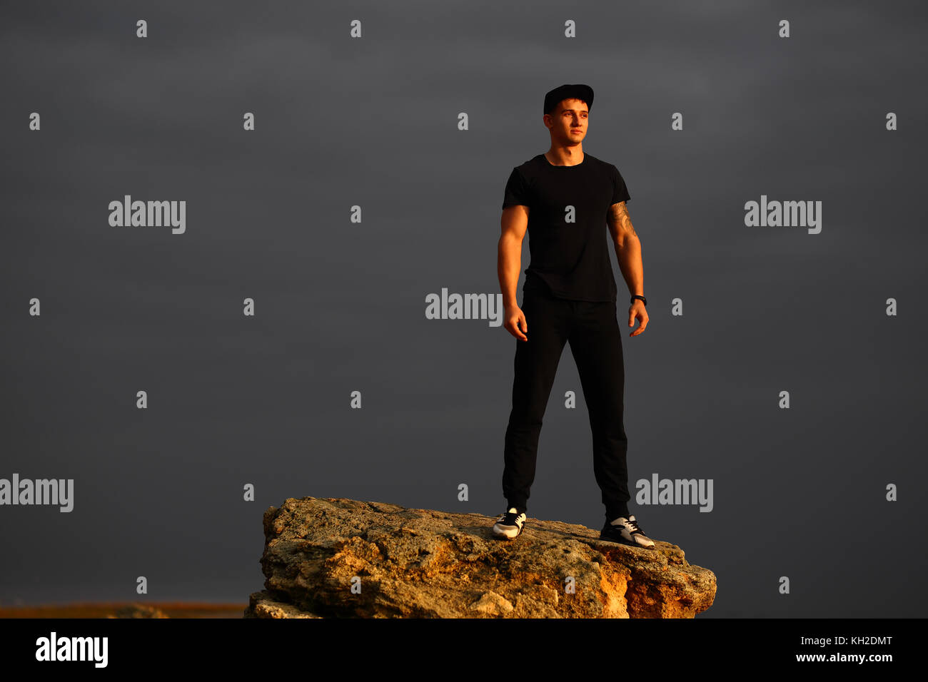 Homme debout sur la plage rocheuse dans le coucher du soleil sur la mer. Banque D'Images Homme debout sur la plage rocheuse dans le coucher du soleil sur la mer. Banque D'Images
