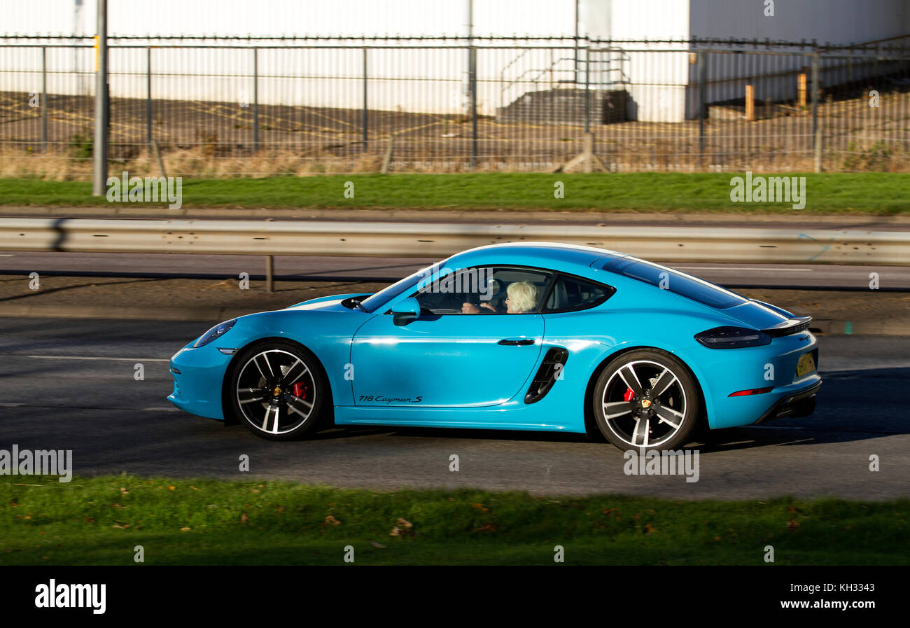 Une petite dame âgée conduisant un bleu à gauche Porsche 718 Cayman S Voiture de sport le long de la route à l'ouest de Kingsway à Dundee, Royaume-Uni Banque D'Images