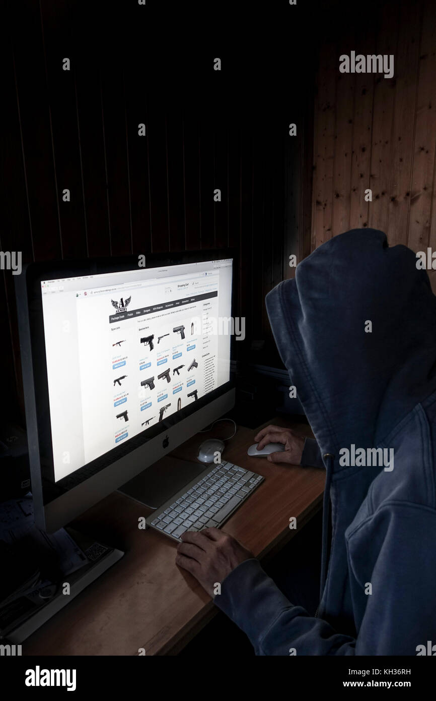 Image Concept de cyber à capuchon, l'homme criminel à l'aide d'ordinateur pour accéder à la page internet web profond offrant des armes à feu, Banque D'Images