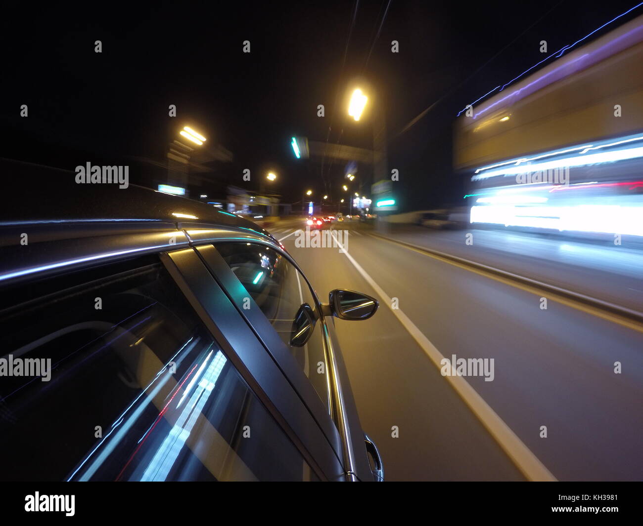 La voiture est en mouvement à grande vitesse sur la route de nuit dans la ville. L'emplacement de la caméra latérale sur la caisse. Banque D'Images