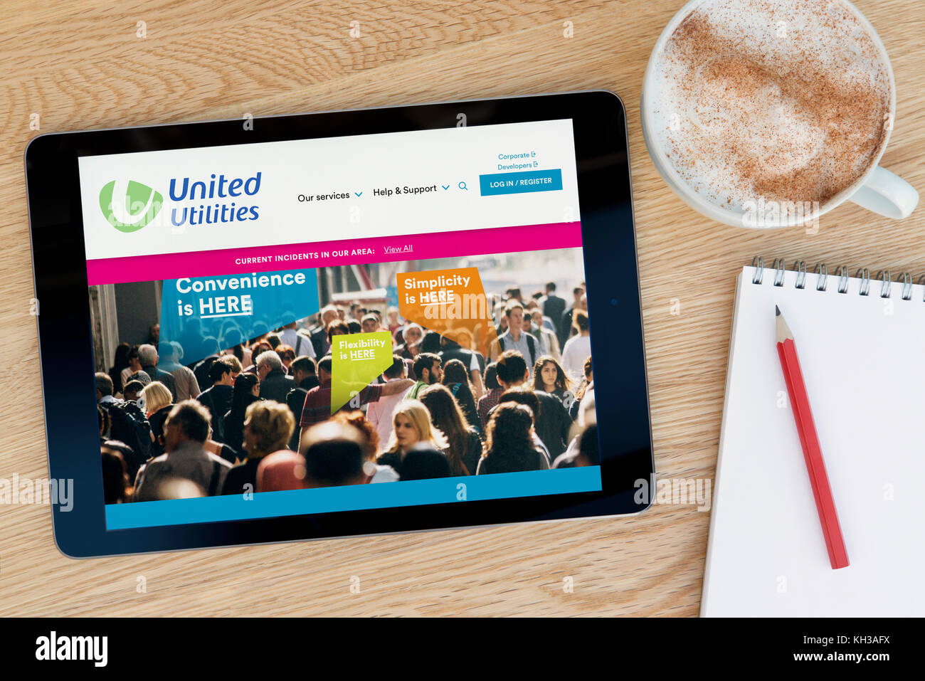 Le site web de United Utilities fonctionnalités sur un iPad tablet device qui repose sur une table en bois à côté d'un bloc-notes et un crayon et une tasse de café. Banque D'Images