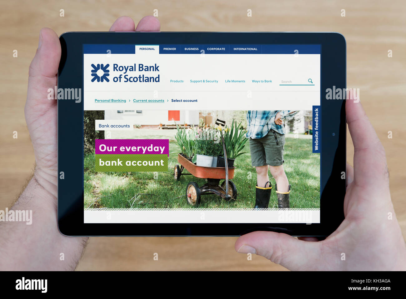 Un homme regarde la banque RBS site sur son iPad tablet device, tourné contre une table en bois page contexte (usage éditorial uniquement) Banque D'Images
