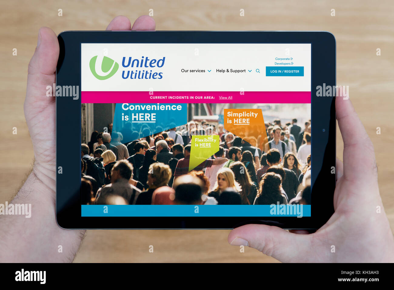 Un homme regarde le site web de United Utilities sur son iPad tablet device, tourné contre une table en bois page contexte (usage éditorial uniquement) Banque D'Images