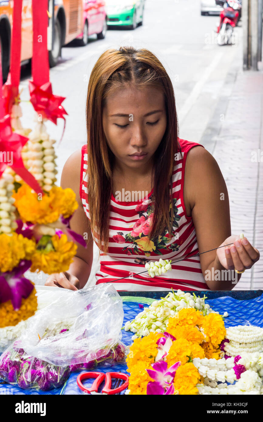 Jeune fille faire des guirlandes de fleurs sur une rue de Bangkok, Thaïlande Banque D'Images