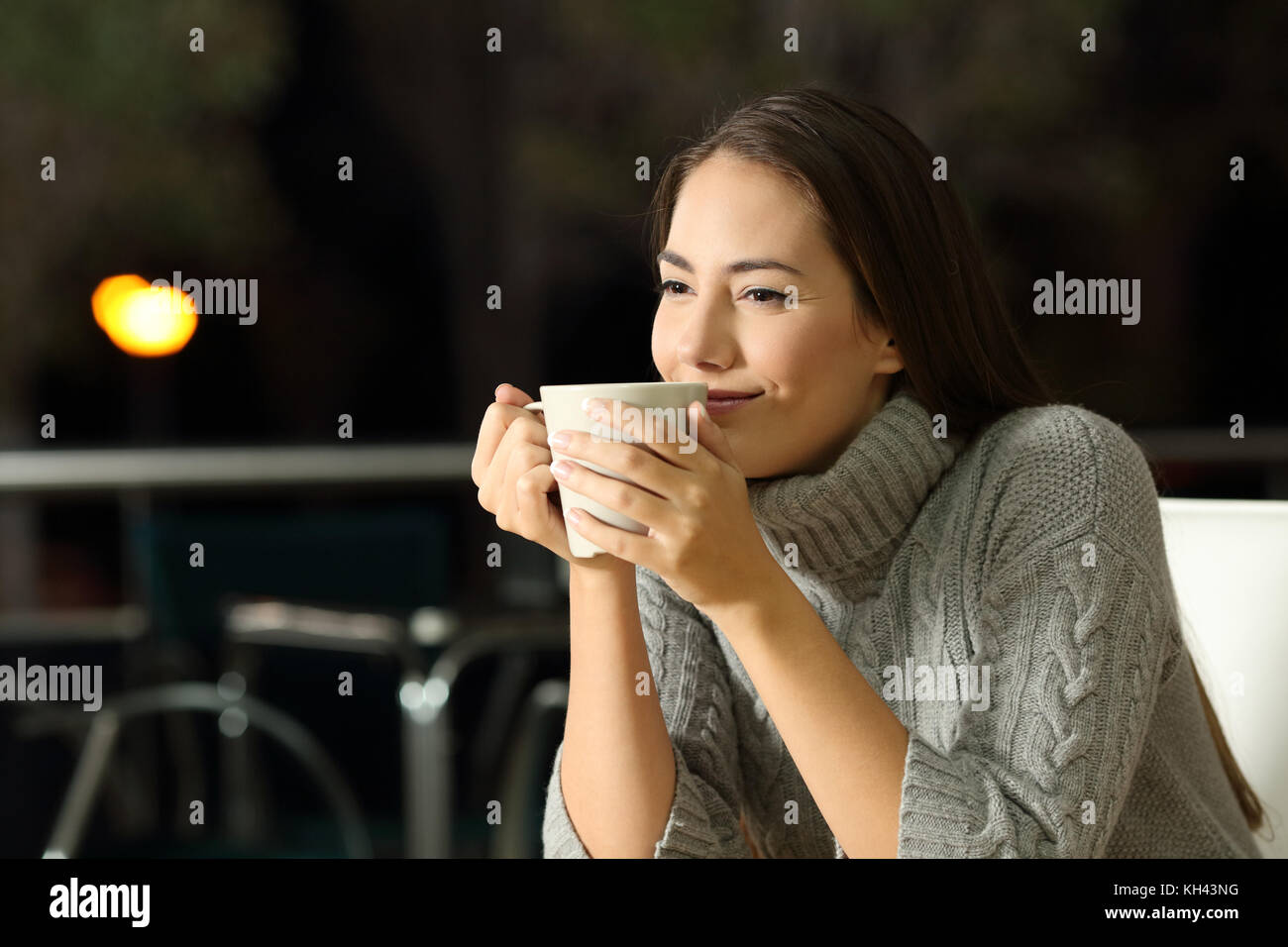 Portrait of a smiling woman enjoying cofee dans un bar de nuit en hiver Banque D'Images
