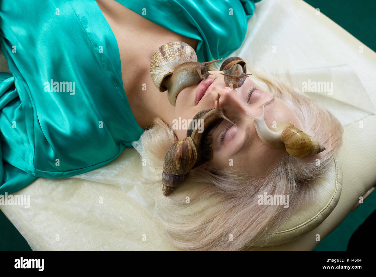 Portrait de jeune femme avec les escargots sur le visage. Jolie blonde recevoir massage du visage avec des escargots en instituts de beauté et de régénération de traitement de la peau.. Banque D'Images