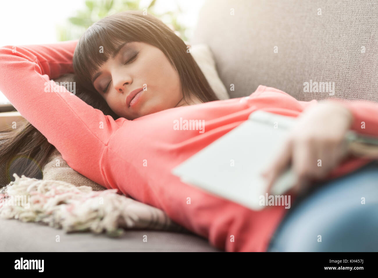 Jolie femme dormir sur le canapé avec les yeux fermés, elle lisait un livre Banque D'Images
