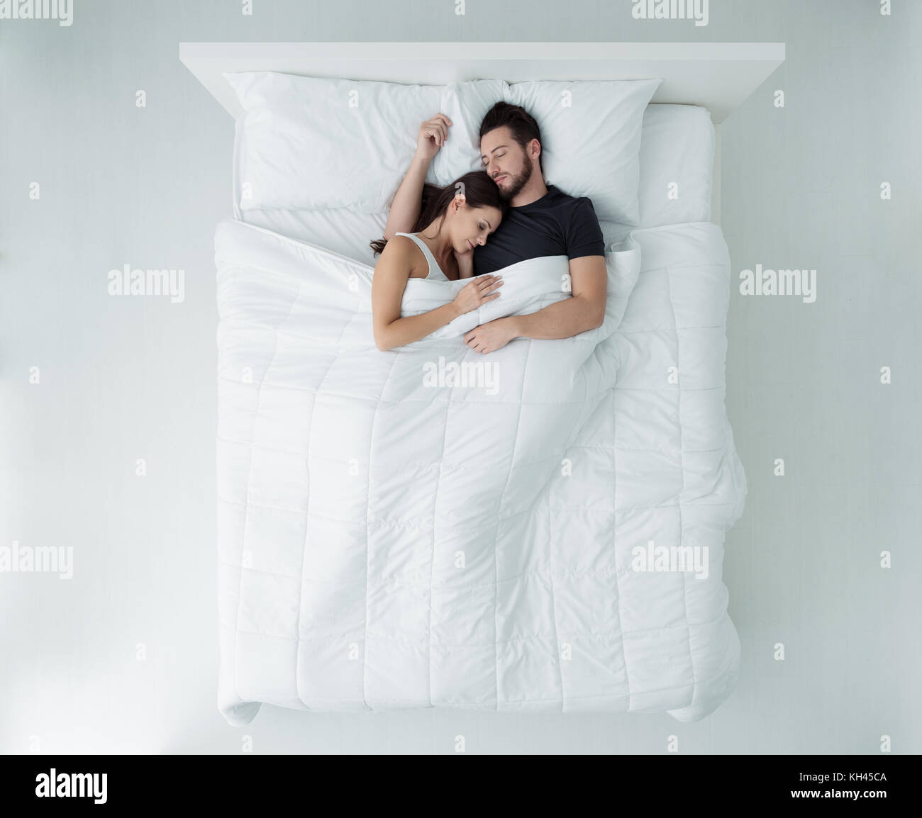 Jeune couple aimant dormir dans le lit, ils sont câlins, vue d'en haut Banque D'Images