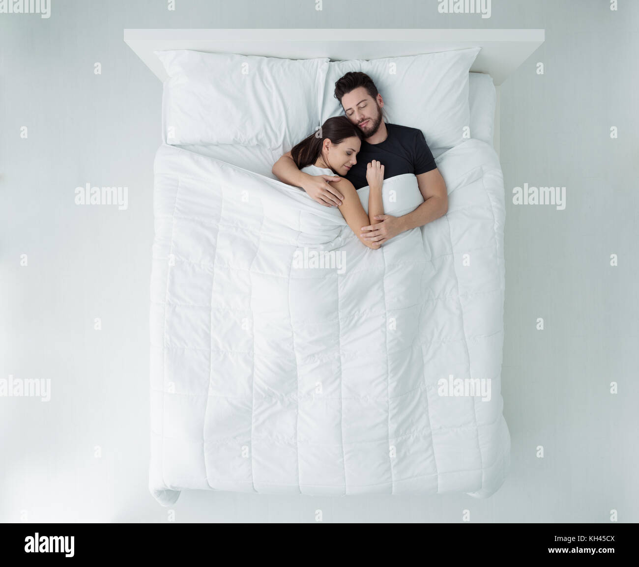 Jeune couple aimant dormir dans le lit, ils sont câlins, vue d'en haut Banque D'Images