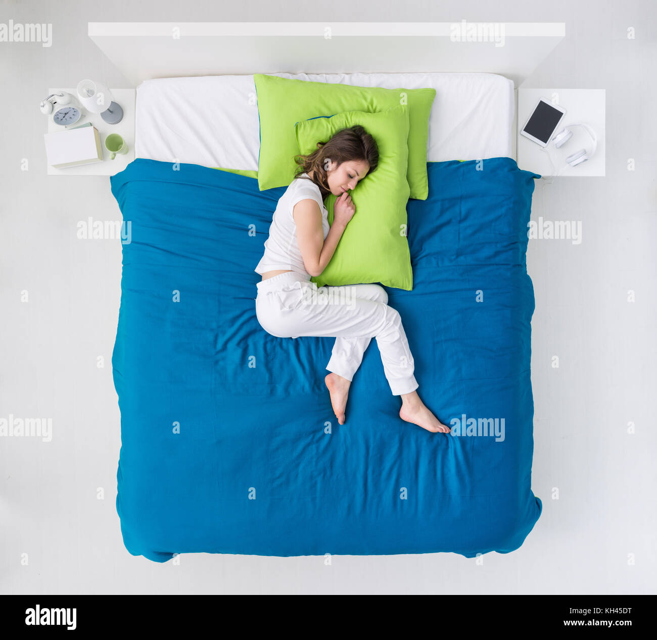 Jeune femme dormir dans sa chambre, elle est le curling sur la couette et serrant un oreiller Banque D'Images