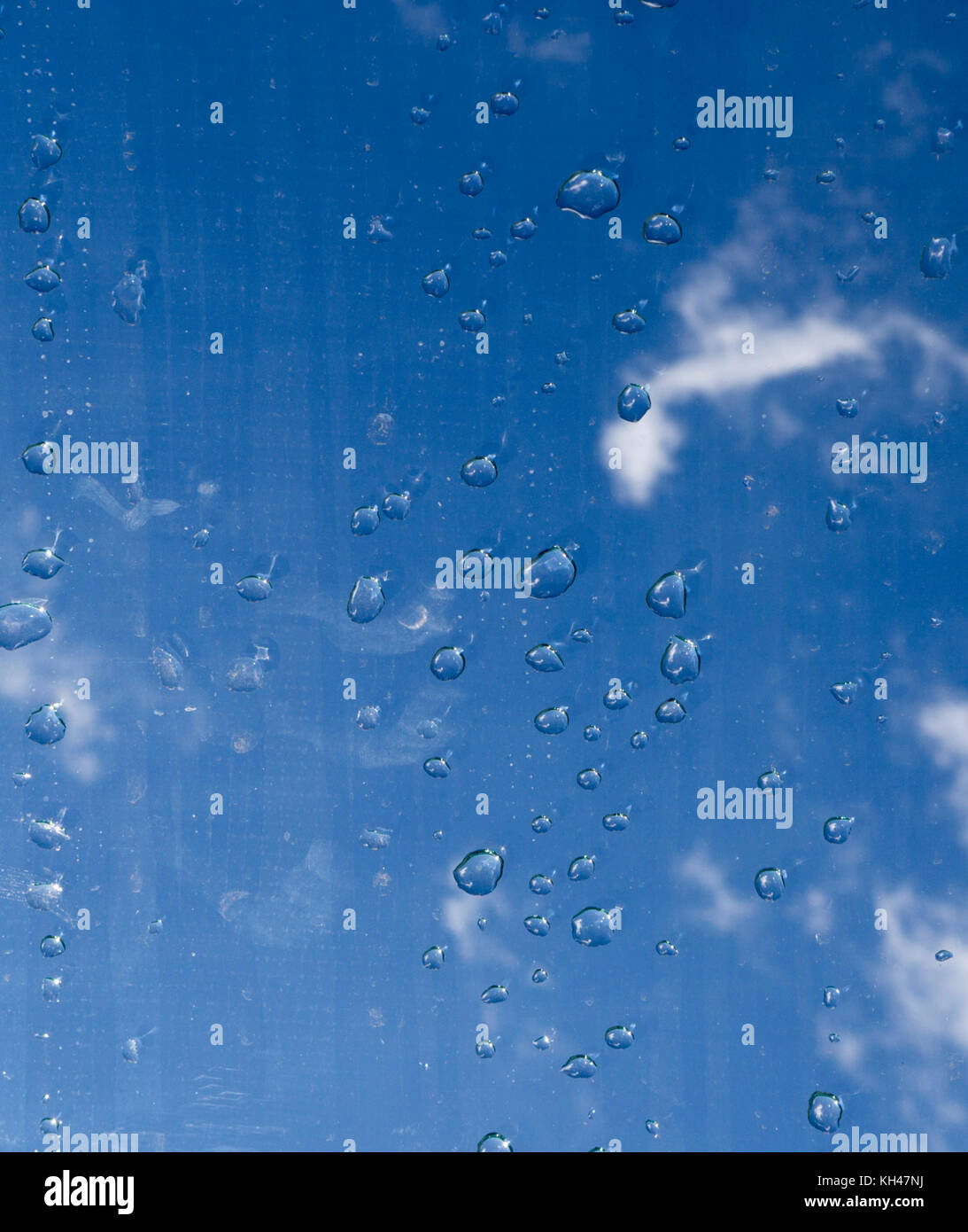 Gouttes d'eau sur le verre sous le ciel. La texture, l'arrière-plan. Banque D'Images