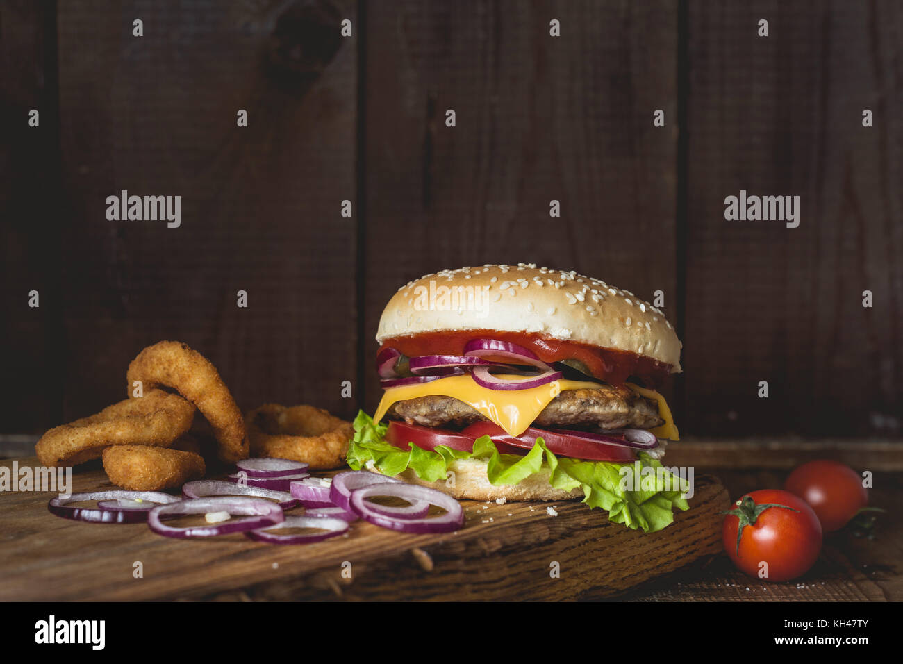 Cheeseburger et oignons sur planche à découper en bois sur fond de bois. Vue rapprochée avec copie espace pour le texte Banque D'Images