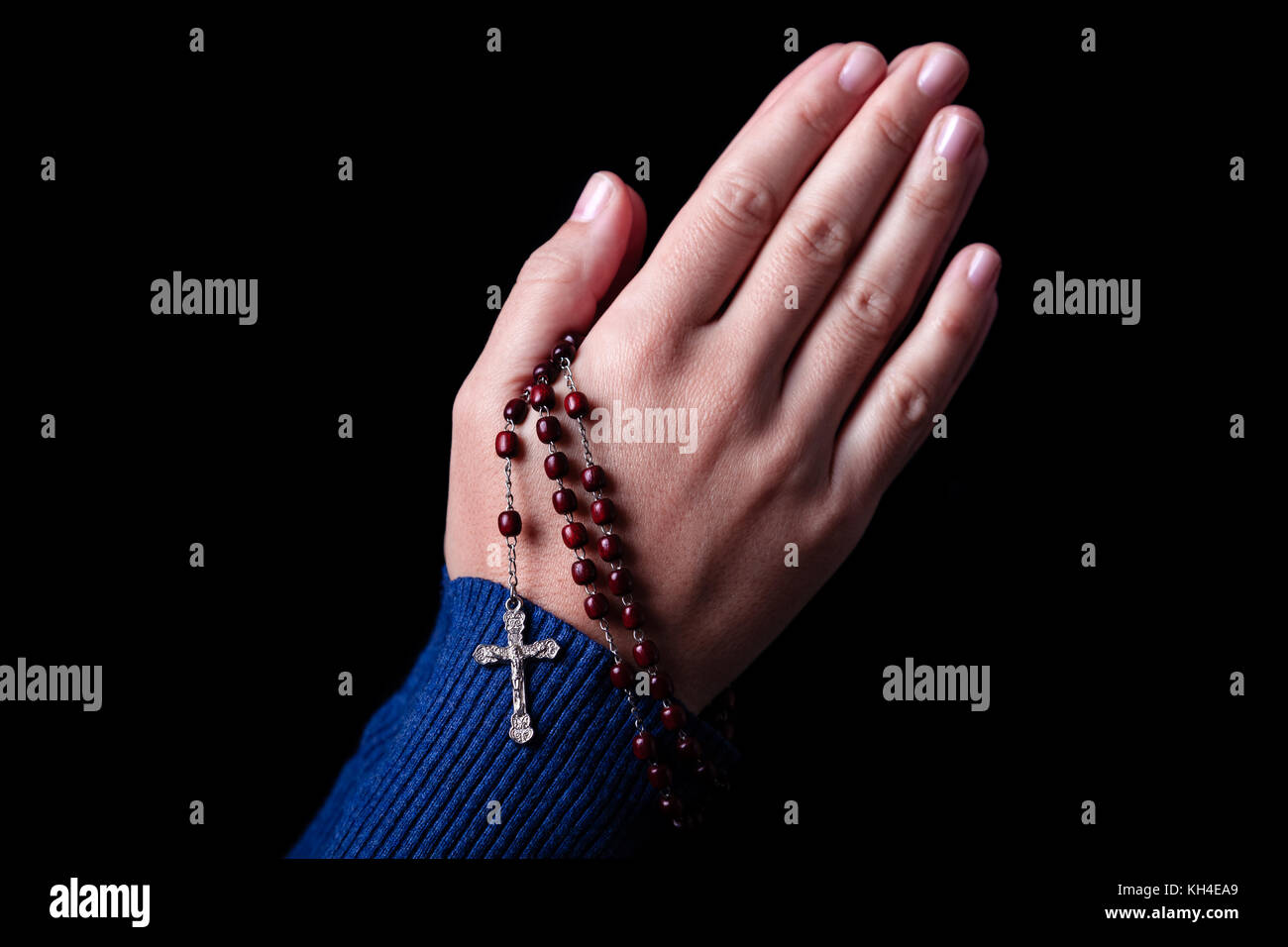 Femme priant mains tenant un rosaire avec Jésus Christ dans la croix ou crucifix sur fond noir. femme avec la foi chrétienne catholique Banque D'Images