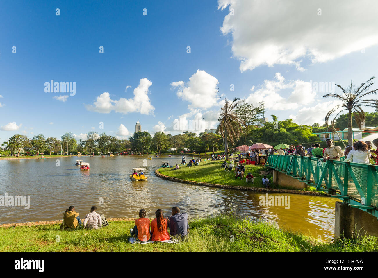Personnes à pied et assis dans Uhuru Park par le lac de plaisance regardant peddle bateaux, Nairobi, Kenya Banque D'Images