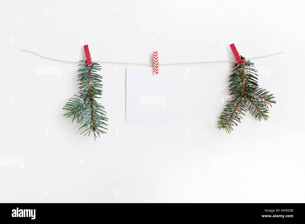 Feuille de papier blanc accroché sur le chiffon et chevilles en bois avec corde branches de sapin de Noël vert, une maquette modèle. Banque D'Images