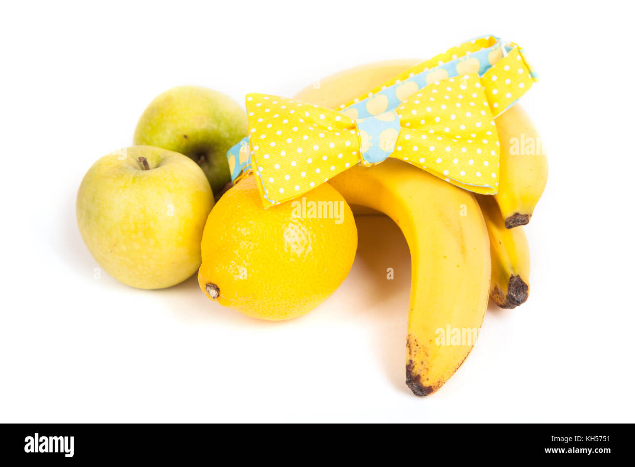 Composition, un noeud papillon jaune se trouve sur le côté de la banane, pommes jaunes, entre le citron Banque D'Images