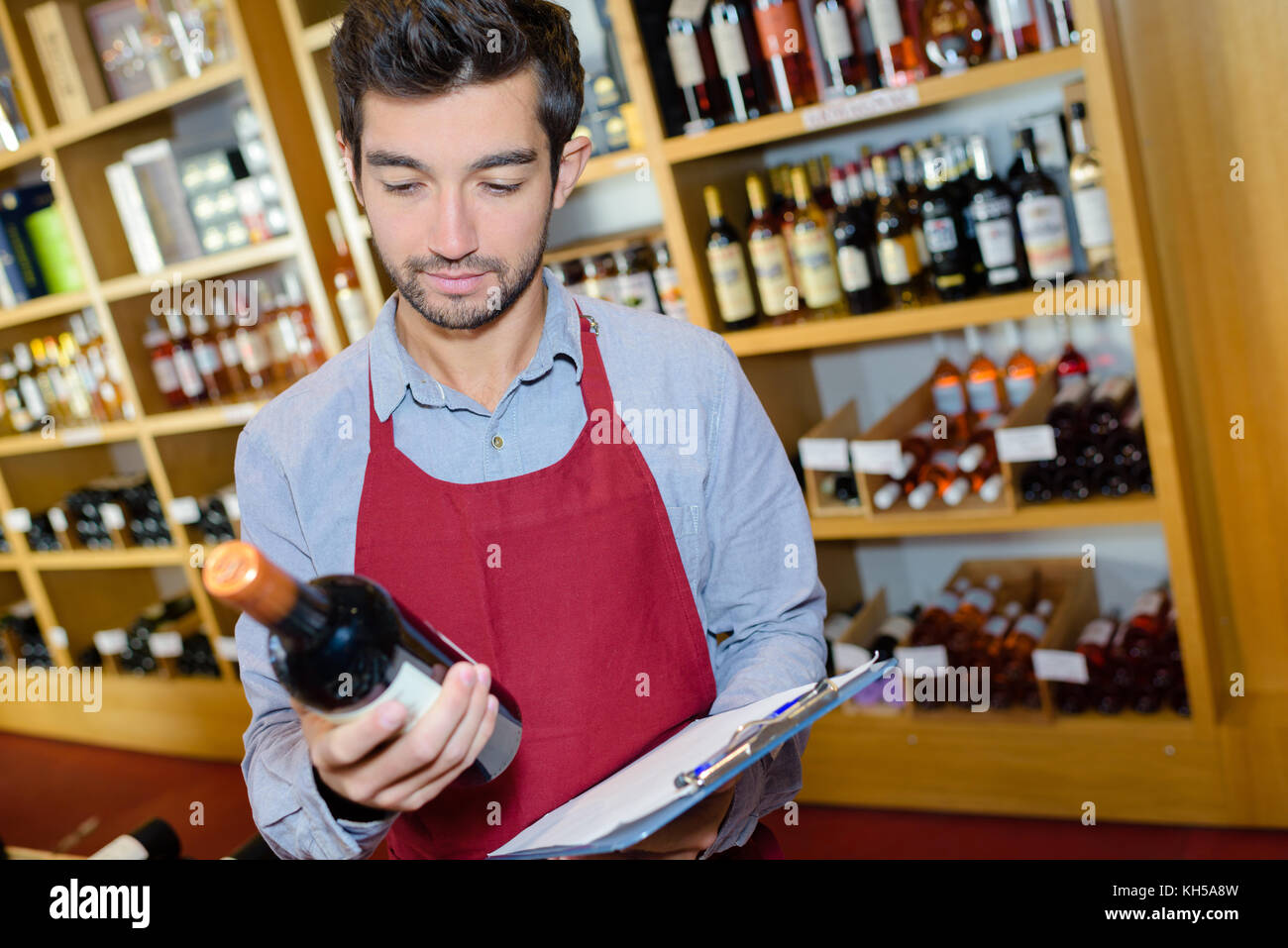 Sommelier avec bouteille de vin debout près des étagères bien garni Banque D'Images