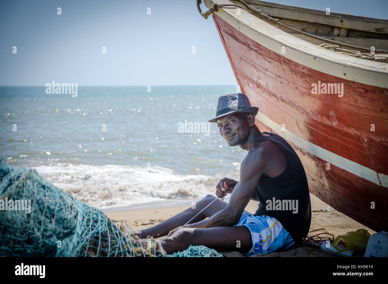 LOBITO, ANGOLA - Mai 09 2014 non identifié : pêcheur angolais assis en face de la plage bateau de pêche à filets de fixation Banque D'Images