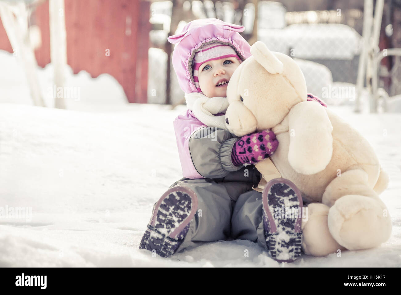Faire place au beau bébé ours en peluche jouet assis sur la neige dans un parc à jour d'hiver ensoleillé froid pendant les vacances d'hiver Banque D'Images