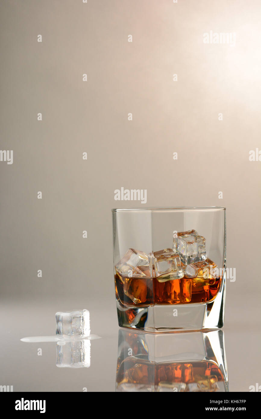 Le scotch sur les rochers sur une table en verre avec un cube de glace fondante Banque D'Images